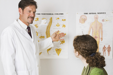 Chiropractor using *generic* charts to explain the spinal column to a patient.