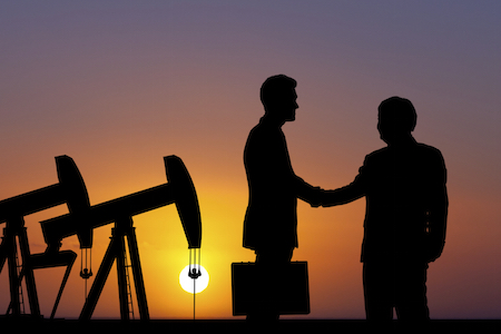 oil and gas factoring business deal handshake in front of oil rigs