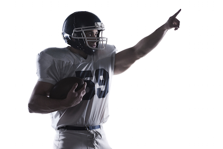 Over there! American football player holding ball and pointing away while standing against white background